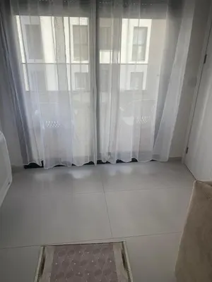 a white room with a large window with curtains at Flamur Ujkashi in Ulcinj