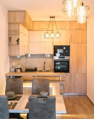 a kitchen with wooden cabinets and a table with chairs at Royal Apartment in Ulcinj