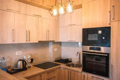 a kitchen with wooden cabinets and a black microwave at Royal Apartment in Ulcinj