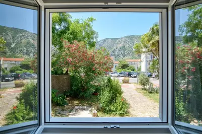 a window view of a garden with mountains in the background at Apartment Seaside in Kotor