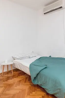 a white bedroom with a bed and a table at Cozy Studio Budva in Budva