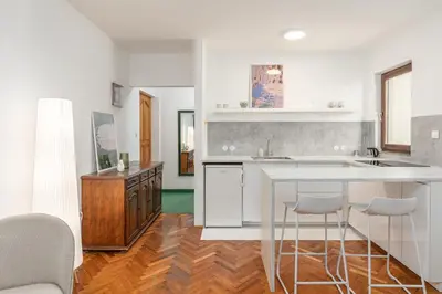 a kitchen with white cabinets and a counter with bar stools at Cozy Studio Budva in Budva