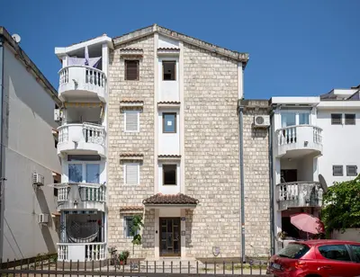 an apartment building with balconies and a red car parked in front at Cozy Studio Budva in Budva