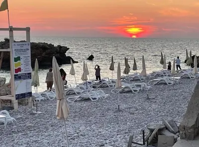 a beach with chairs and umbrellas at sunset at Apartments Dana Seaview in Bar