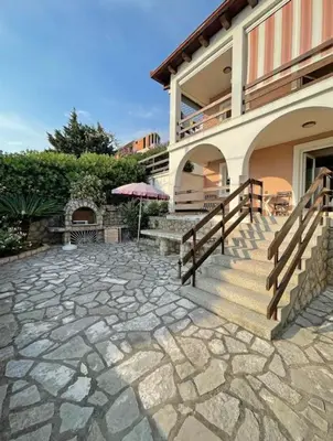 a house with a patio with a staircase and an umbrella at Apartments Dana Seaview in Bar