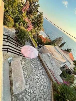 a pink umbrella and a bench next to the water at Apartments Dana Seaview in Bar