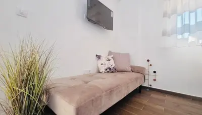 a couch with a television on a white wall at Boljevic Apartments in Becici