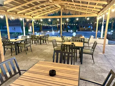 a restaurant with wooden tables and chairs and lights at Neptun Beach & Forest Cabins in Ulcinj