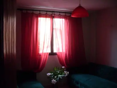 a room with a window with red curtains and a green couch at villa Magnolia in Donji Štoj