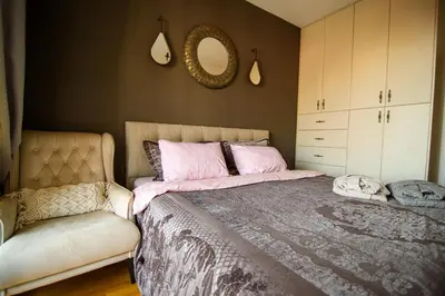 a bedroom with a bed with pink pillows and a chair at Apartment with sea view 5 minutes from the beach in Budva