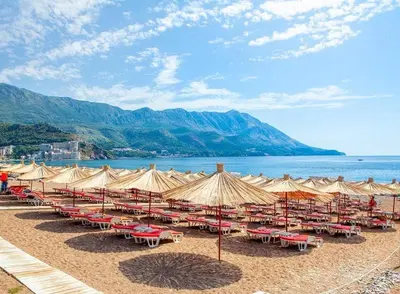 a group of tables and umbrellas on a beach at Apartment with sea view 5 minutes from the beach in Budva