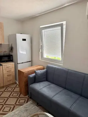 a living room with a blue couch and a refrigerator at Tatjana apartman blue in Sutomore
