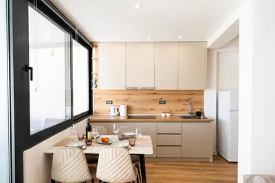 a kitchen with white cabinets and a table with chairs at Latković Charming Studio in Ulcinj