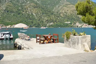 a dock with a table and chairs next to the water at Kuzman Apartments in Kotor