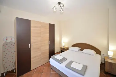 a bedroom with a white bed and a wooden cabinet at Kuzman Apartments in Kotor