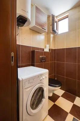 a small bathroom with a washing machine and a toilet at Cihan Apartment in Budva