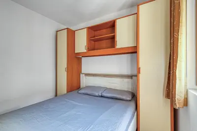 a small bedroom with a bed and wooden shelves at Cihan Apartment in Budva