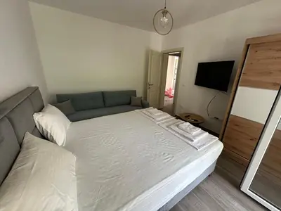 a bedroom with a white bed and a television at Apartman Aki 2 in Bar