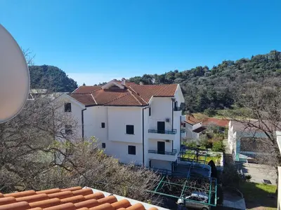 a large white building with a mountain in the background at Apartment Natasha in Petrovac na Moru