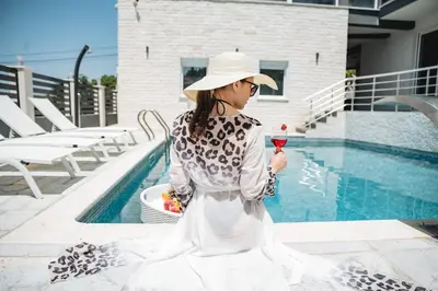 a woman holding a glass of wine next to a pool at Villa Blue Haven in Ulcinj