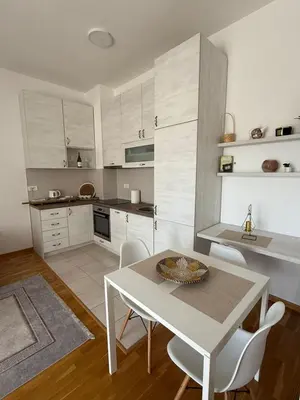 a kitchen with a white table and white chairs at Apartman Luka in Bar