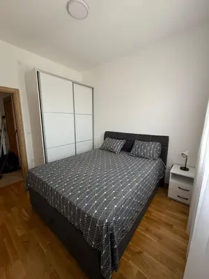 a bedroom with a bed and a white wall at Apartman Luka in Bar