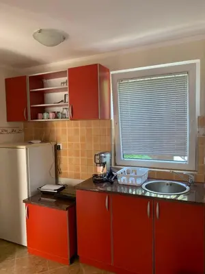 a kitchen with red cabinets and a sink and a refrigerator at Čanj apartmani in Čanj