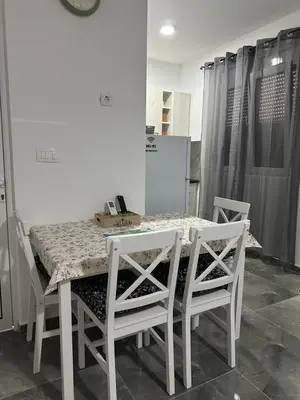 a dining room table with four white chairs and a table and chairsuggest at Apartman 2 in Bar, Susanj
