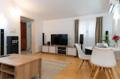 a living room with a table and white chairs at Airport Apartments Una in Mitrovići