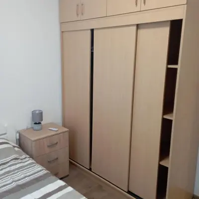 a bedroom with wooden cabinets and a bed and a dresser at Nice summer apartment near sea in Budva