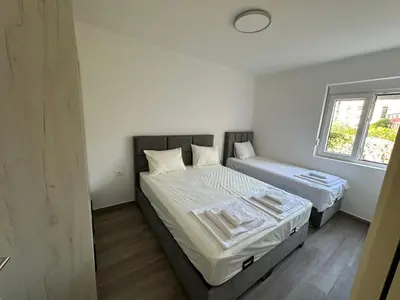 a bedroom with two beds and a window at Apartmani Aki 3 in Sutomore