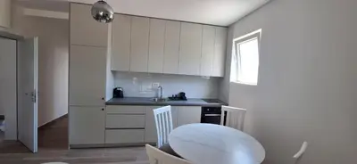 a kitchen with white cabinets and a sink and a table at Apartmani Aki 3 in Sutomore