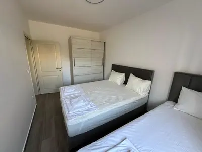 a bedroom with two beds and a clock on the wall at Apartmani Aki 3 in Sutomore