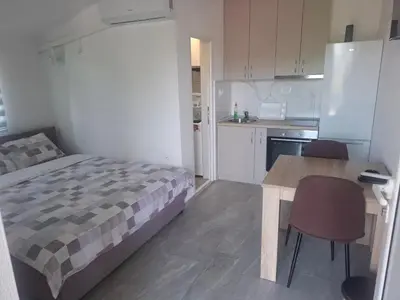a bedroom with a bed and a table and a kitchen at Apartman Andjela 1 in Budva