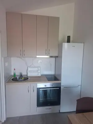 a kitchen with white cabinets and a sink and a refrigerator at Apartman Andjela 1 in Budva