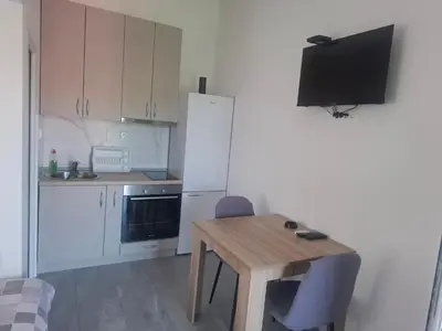 a small kitchen with a wooden table and a television at Apartman Andjela 1 in Budva