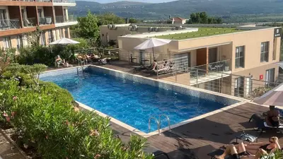 a swimming pool at a hotel with people sitting around it at Casa Montenegro 1 Plus 1 Suite View Sea and Pool in Kavač