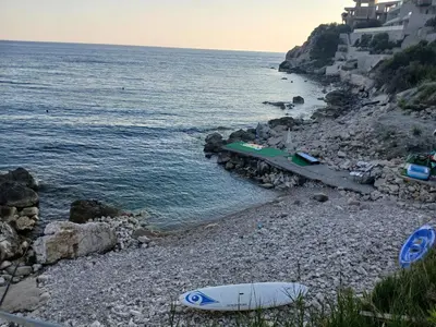 a surfboard on a rocky beach next to the water at MonaLiza in Ulcinj