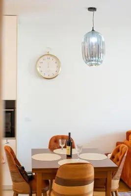 a dining room with a table with a bottle of wine and a clock at Lovely onebedroom Becici in Becici