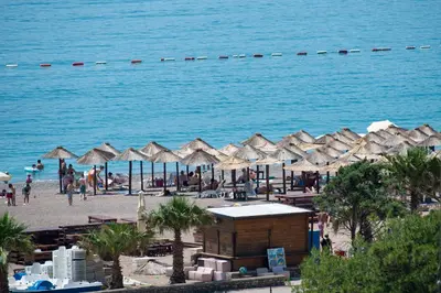 a beach with umbrellas and people on the beach at Lovely onebedroom Becici in Becici