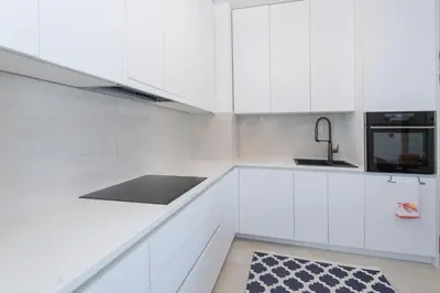 a white kitchen with white cabinets and a sink at Lovely onebedroom Becici in Becici