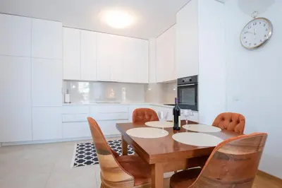 a kitchen with a wooden table with chairs and a clock at Lovely onebedroom Becici in Becici