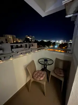 a table and two chairs on a balcony at night at Apartman Kutak in Bar