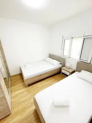 a white room with two beds and two windows at Asia Apartments in Škaljari