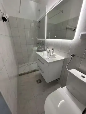 a white bathroom with a sink and a mirror at Asia Apartments in Škaljari