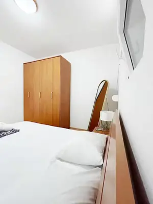 a bedroom with a bed and a wooden cabinet at Asia Apartments in Škaljari