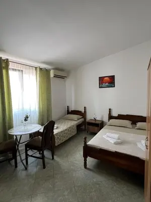 a room with two beds and a table and a table and chairs at Apartmani Zlatičanin in Sutomore