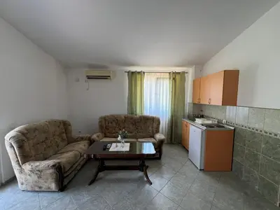 a living room with a couch and a table and a kitchen at Apartmani Zlatičanin in Sutomore