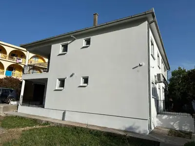 a large white building with a large door at Apartmani Aki 1 in Sutomore