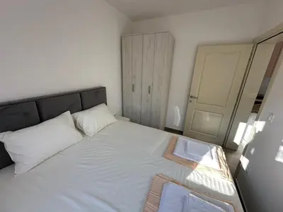 a bedroom with a large white bed with a mirror at Apartmani Aki 1 in Sutomore